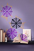 Hand-made paper spiders' webs on purple wall