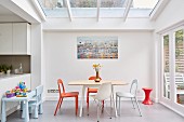 Bright dining area below skylight in extension to period building with French windows