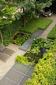 Pond, grating jetty, ground-cover plants and outdoor furniture in geometric garden