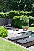 Loungers next to pool in well-tended garden