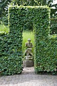 Sculpture framed by opening in clipped hedge