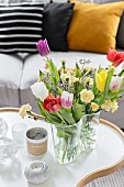 Colorful spring flowers in glass Aalto vase on organically formed coffee table
