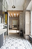 Cement-tiled floor, exposed masonry, shutters and console table in vintage-style hallway