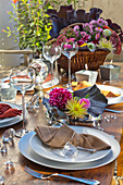 Gedeckter Tisch im herbstlichen Garten, dekoriert mit Rotkohl, Astern und Dahlien