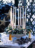 Hedera wreath in the cup with stick candles, ice stars and mahonia