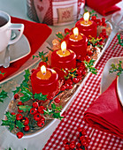 Rote Kerzen in länglicher, weißer Porzellanschale, dekoriert mit Engelshaar