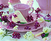 Purple and white syringa flowers on pink place setting, heart with text