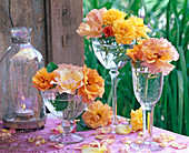 Flowers of roses, yellow and orange, in glasses on the table