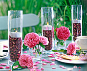 Windlichter in hohen Gläsern mit getrockneten Blütenblättern von Rosa (Rosen)