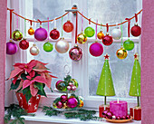 Girlande aus Weihnachtsbaumkugeln ins Fenster gehängt