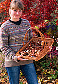 Young woman with tulip bulbs in wicker basket with handle