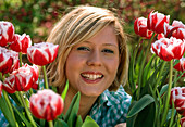 Frau zwischen Tulipa ' Wirosa' (Tulpen)