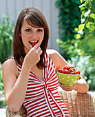 Young woman eating fragaria (strawberries)