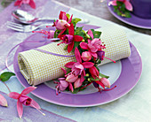 Napkin decoration with fuchsia around rolled napkin