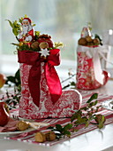 Rot-weißer Nikolausstiefel mit roter Schleife, gefüllt mit Nüssen, Apfel