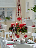 Gemischter Adventskranz mit roten Kerzen über dem Tisch aufgehängt
