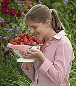 Young woman enjoying the smell of freshly picked strawberries