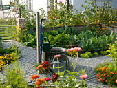 Cottage garden with fountain in the middle, flower beds with vegetables, salad, herbs