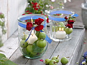Preserving jars as lanterns with candles on green apples