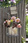 Glass in wire basket as lantern with blackberry vine and pink