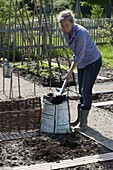 Woman removing potting soil to improve the soil in the bed