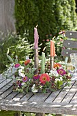 Wreath of Lathyrus odoratus (scented vetches) and zinnias around candlestick on table