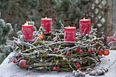 Advent wreath of mossy branches on metal frame with candle holders