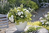 Green and white bouquet on garden table alchemilla, pink
