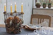 Wire basket as a 5-minute Advent wreath with yellow candles, cones