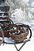 Snow covered baskets with different pine cones on chair