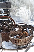 Snow covered baskets with different pine cones on chair