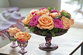 Roses arrangement with moss in shallow footed bowl and glass