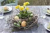 Easter table decoration with wreath of twigs, grasses and yellow primrose