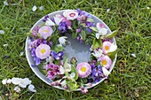 Colorful spring wreath in cup with water in the grass