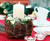 Candle decoration decorated with pine cone, clay pot with pine cones and fruits
