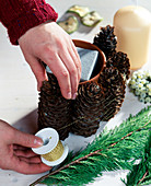 Candle decoration with pine cones - pine cones with gold wire around the clay pot