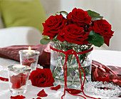Rote Rosen in Glas mit Glaskugeln und Windlichtern.