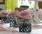 Rosa Rosenblüten in Vasen aus Glas und Eisen