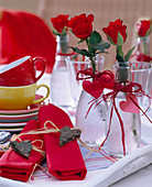Rosa / rote Rosen in Glasflaschen mit Herzen aus Pappe