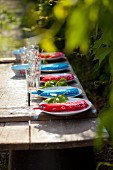 Bandana-Tücher als Bestecktaschen auf rustikalem Holztisch im Garten