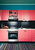 Renovated kitchen with red cupboards and black-tiled splashback