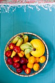 Round basket of fruit on blue wooden floor