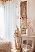 Flowers on side table and Madonna figurine in shabby-chic interior