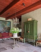 Green-painted Swedish cupboard and table under French 19th-century glass chandelier