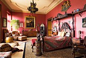 Antikes Holzbett mit Schnitzereien in rotem Schlafzimmer mit Ölportrait in Goldrahmen