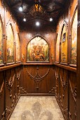 Wood-panelled elevator with coffered ceiling and biblical imagery