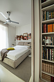 View into beige bedroom past bookcase