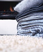 Stack of grey blankets on rug in front of fireplace