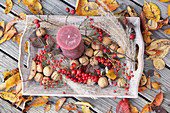 A candle, walnuts, red berries and reeds