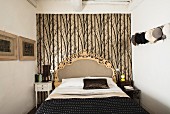 Bed with opulent headboard against patterned wallpaper